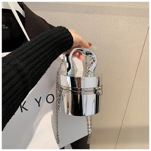 Detail of silver mirrored cylindrical acrylic clutch bag with metal chain and top handle