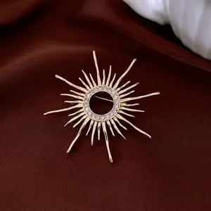 Vintage style gold-plated sunburst brooch with pavé zircon stones on dark silk background