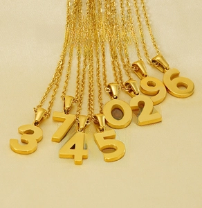 Detailed macro view of 18K gold plated stainless steel number pendants with mirror finish