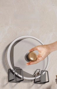 Macro view of gun grey wall-mounted lid rack holding a glass lid on marble background
