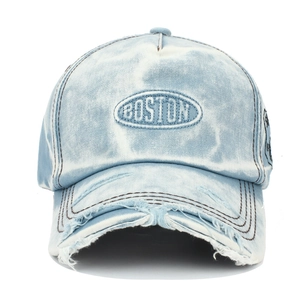 Detailed view of Boston embroidery and distressed ripped brim on washed denim baseball cap