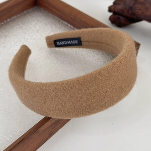Detail shot of brown felt headband with handmade label on textured wooden tray