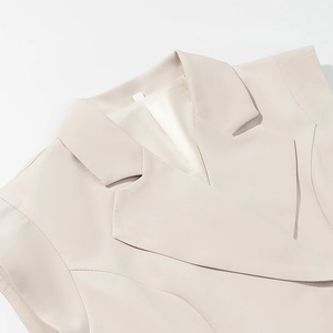 Detail of a beige sleeveless blazer vest showing the classic notched lapel and smooth fabric