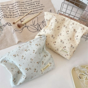 Floral makeup bags in light blue and cream white showing canvas texture and zipper details