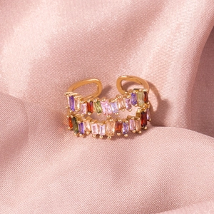 Macro detail of gold double-row ring with colorful rectangular crystals on pink silk