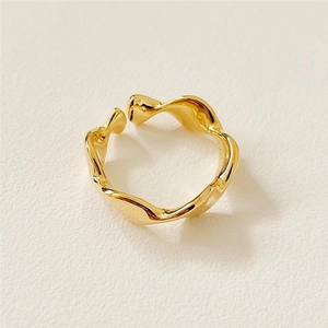 Detailed close-up of golden irregular wavy ring with a minimalist polished metal texture