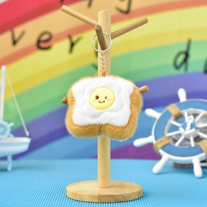 Close-up of cute plush toast pendant with winking fried egg embroidery and metal keychain