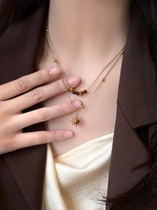 Close-up of a double-layer gold sun pendant necklace with tiger eye stone beads
