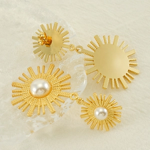 Boucles d'oreilles vintage en perles dorées en forme de soleil sur un tissu crème texturé