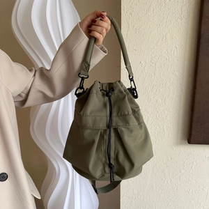 Gros plan du sac seau vert olive avec fermeture à cordon et détails métalliques noirs