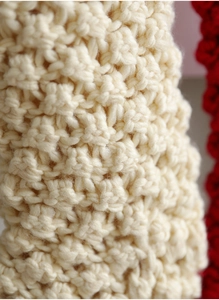 Macro detail of cream cable knit texture with red trim on a large Christmas stocking
