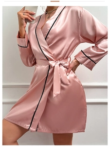 Détail d'un peignoir en satin rose avec liseré noir et ceinture ajustable à la taille