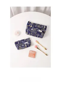 Detail of navy cotton linen cosmetic bags with gold floral embroidery on a white table