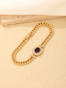 Detailed close-up of a golden Cuban chain bracelet with a purple oval zircon centerpiece