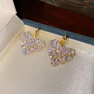 Gros plan de boucles d'oreilles cœur en or avec zircons dans un écrin bleu élégant