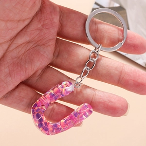 Close-up of letter U keychain with pink and purple sequins in transparent resin