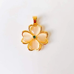 Detailed close-up of pink cat eye stone clover pendant with gold plating and green gem