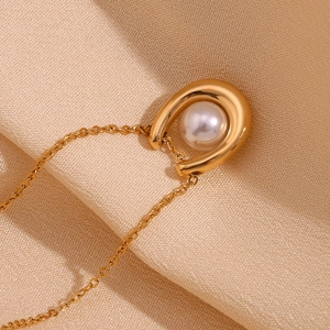 Close-up of 18K gold U-shaped horseshoe pendant necklace with a pearl on silk