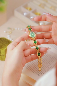 Elegant gold bracelet watch for women featuring green emerald-like dial and crystal accents