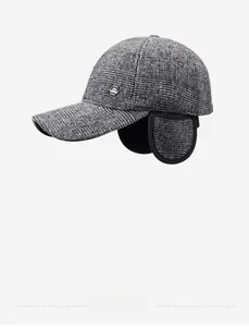 Close-up of winter baseball cap with ear flaps and metal logo on grey plaid fabric