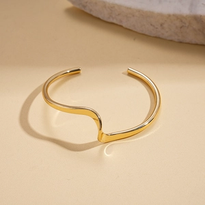 Detail view of gold geometric wave cuff bracelet with smooth polished finish and artistic lines