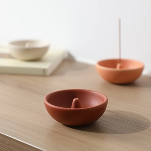 Soportes de incienso cerámicos minimalistas en tonos tierra sobre madera