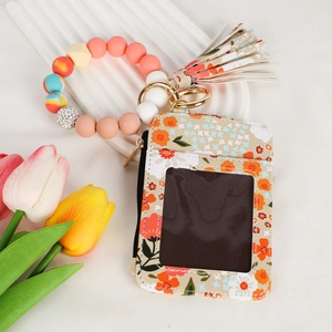 Close-up of floral zipper card wallet with silicone bead bracelet and orange tassel detail