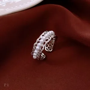 Lace hollow pearls open ring in silver finish on a luxury red velvet background