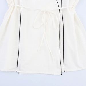 Detail of white cotton-linen fabric with black contrast piping and bow drawstring tie