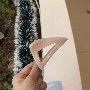 Detail shot of a peach triangle hair claw clip with a glossy finish and hollow design