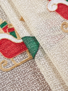 Detailed macro shot of festive Santa Claus embroidery on beige woven Christmas tablecloth