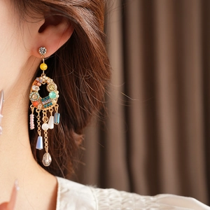 Détail de boucles d'oreilles bohèmes dorées avec pierres précieuses et glands perlés