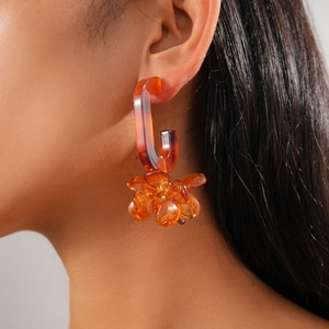 Close-up of model wearing orange resin flower earrings in a vintage oval C-shape design