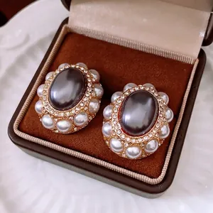 Vintage gold oval earrings with gray stones and pearls displayed in a velvet box