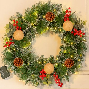 Detail of flocked Christmas wreath with LED lights, pine cones, and red berries