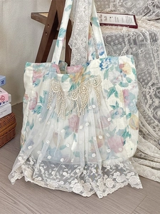 French floral linen tote bag with white lace overlay and fringe in a rustic setting