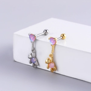 Macro detail of bear-shaped stud earrings with pink opal stones in silver and gold finish