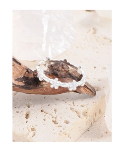 Close-up of silver floral relief ring on natural wood with travertine background