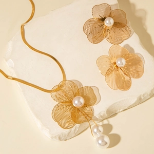 Détail macro de la parure ginkgo dorée avec perles blanches et chaîne serpent