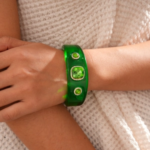 Close-up of green resin bangle with square gemstone worn on a beige sweater