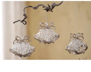 Three clear acrylic bell ornaments with gold glitter trim hanging on a branch