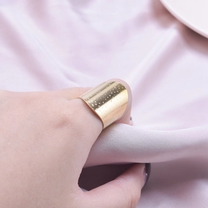 Minimalistischer breiter goldener Edelstahlring mit Punkttextur am Daumen getragen