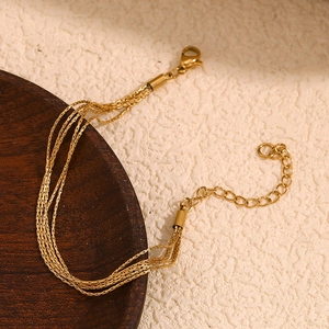 Layered 18K gold plated stainless steel chain bracelet on a rustic wooden tray