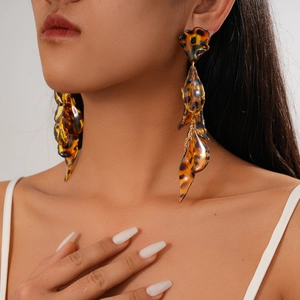 Close-up of leopard print acrylic drop earrings with amber tortoiseshell petals on model