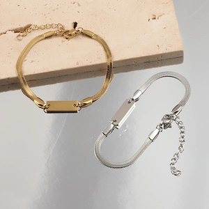 Sleek gold and silver flat snake chain bracelets with engravable plates on stone