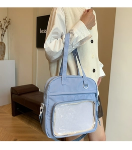 Detail of light blue crossbody bag featuring a transparent front compartment for badges