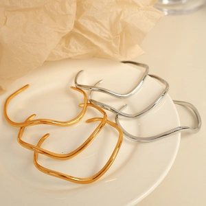 Bracelets vintage ondulés dorés et argentés sur une assiette en porcelaine blanche