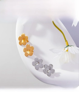 Detail view of gold and silver five-petal flower earrings with PVD electroplated finish