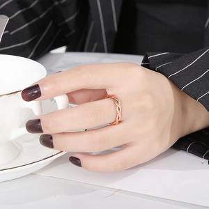 Close-up of twisted woven ring in rose gold on model holding a white coffee cup