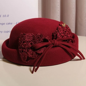 Close-up of wine red wool beret featuring lace bow and golden heart metal buckle